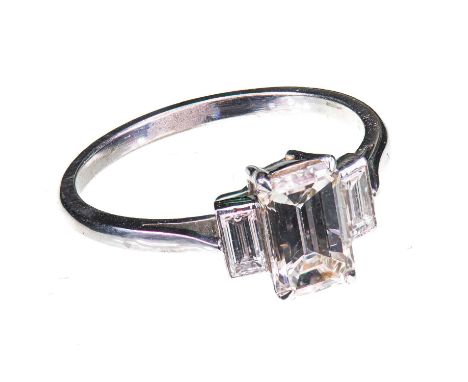 A DIAMOND THREE STONE RING unmarked, the central emerald-cut diamond, flanked by two smaller baguette-cut diamonds. Estimated