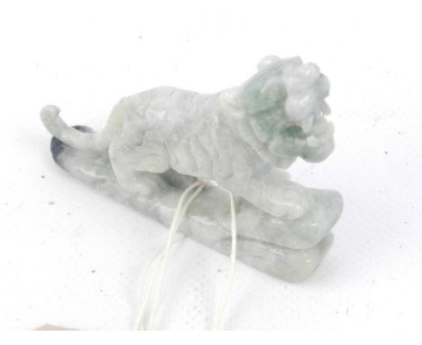 A Chinese carved green jade paperweight in the form of a roaring lion raised on a stylised base. W: 9cm H: 5.5cm