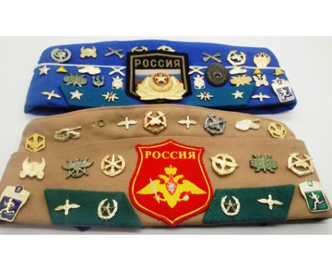 Two Soviet caps, each mounted with a selection of enamelled and cloth badges. P&amp;P Group 1 (£14+VAT for the first lot and 