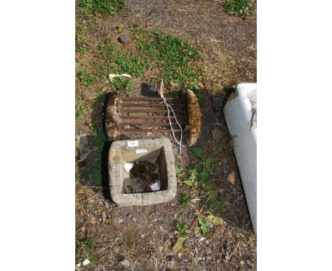 A square concrete planter and metal boot scraper.