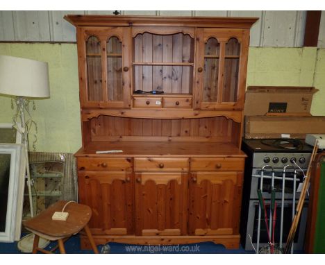 A pine kitchen dresser, 3 drawer over 3 door base with glazed door cupboards and central shelf to back, 54" w x 74" h x 18" d