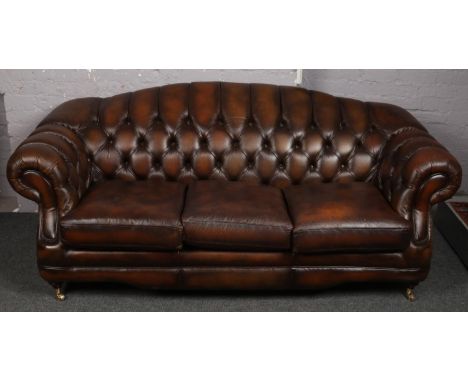 A large brown leather deep buttoned three seat sofa.  