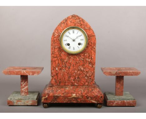 A 19th century French red and grey marble clock garniture. With enamel dial and housing an 8 day Japy Freres cylinder movemen