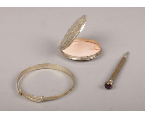 A collection of silver, compact mirror with engraving detailing, bracelet and pencil.  