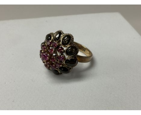 An 18ct gold ruby and black stone set dress ring. Size O.