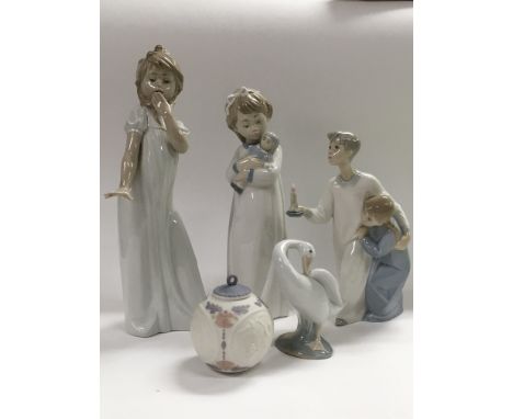 A Lladro figure of a boy and girl holding a candle, a Lladro Duck, a Lladro Christmas bauble and two NAO child figures