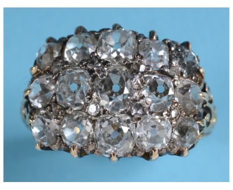 A large diamond cluster ring, set 15 larger old brilliant cut stones interspersed with diamond chips, in a yellow coloured me