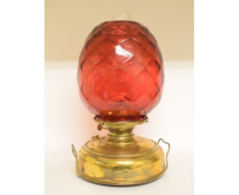 A large oil lamp, with a quilted cranberry glass shade on a brass reservoir, 45 cm high 