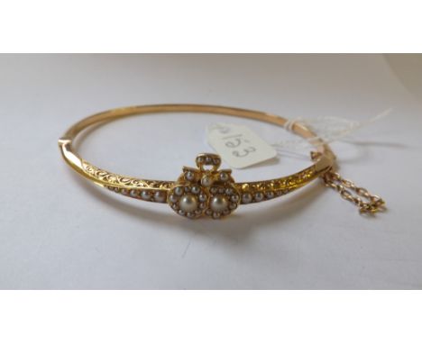 15CT GOLD AND HALF PEARL EDWARDIAN bangle with double heart and bow motif.      