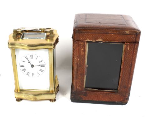 A French brass serpentine carriage clock in case with key. Enamel white dial with Roman numerals. Bevel edge glass panels, on