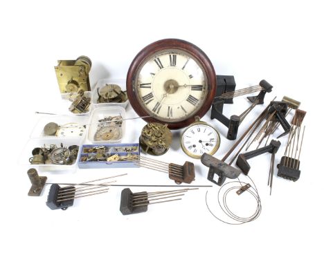 A collection of assorted vintage clock spare parts. In a wooden bin. Including movements, a dial, pendulum, etc.