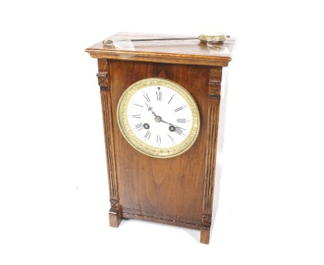 A 20th century mantel clock. The white dial with Roman numerals and a gilt surround, with a pendulum and bell, contained with