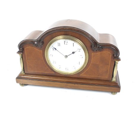 A French mahogany inlaid mantel clock. Brass columns, ball feet and an arched top. White enamel dial with Arabic numerals. H1
