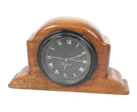 A vintage North & Sons Ltd mechanical car timepiece. Set in a wooden mount, black painted dial with silver Roman numerals, H1