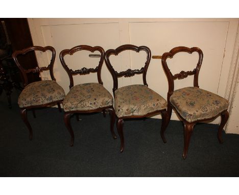 A set of four Victorian mahogany balloon back dining chairs with carved bar backs, tapestry upholstered seats, on cabriole le