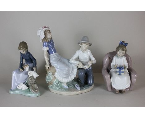 Three Nao porcelain figures, including a seated girl with present, a seated girl with rabbits and a boy bandaging a girl's an