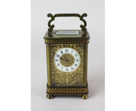 A gilt brass and bevelled glass cased carriage clock, the circular enamel dial with Arabic numerals and gilt scrolling foliat