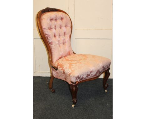 A Victorian button upholstered balloon back chair with carved walnut frame and pink damask upholstery, on scroll feet and cas