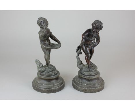 A pair of bronzed spelter figures of a boy playing pipes and a girl holding a dress, on circular bases