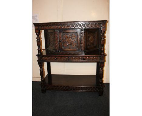 A 20th century carved oak court cupboard of diminutive size with central cupboard and two drawers, with base shelf and balust