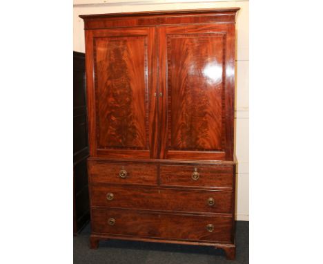 A George III mahogany press cupboard with twin flame veneered panelled doors, on base with two short over two long drawers, o