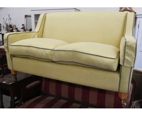 A two-seater Kersey sofa with woven lime fabric and brown piping, light oak tapering square supports and brass castors, 156 x