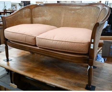 A walnut framed double caned two seater bergere sofa on fluted supports, 130 cm wide x 60 cm deep x 80 cm high 