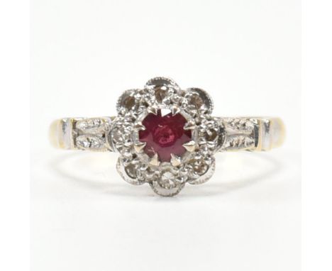 A hallmarked 18ct gold, ruby and diamond cluster ring. The ring having a round cut claw set ruby encompassed by a halo of acc