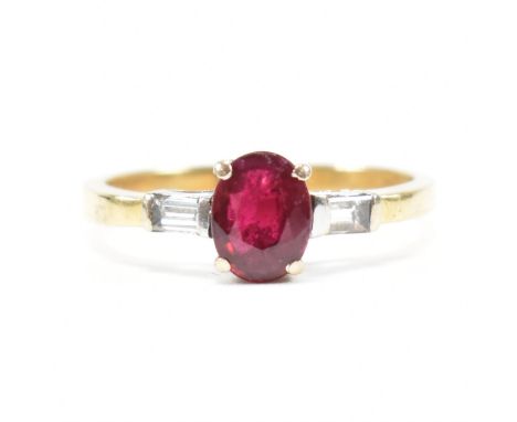 An 18ct gold ruby and diamond ring. The ring set with a central claw mounted ruby and flanked by a pair of baguette diamonds.