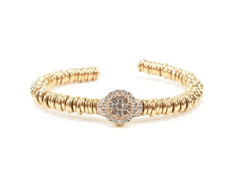 An 18ct yellow gold and diamond cluster bangle bracelet. The cuff bangle comprised of gold ring beads to the central round cu