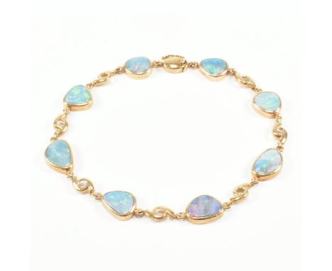 A 9ct yellow gold and opal bracelet chain. The bracelet comprised of organically shaped bezel set opal cabochons spaced by pi