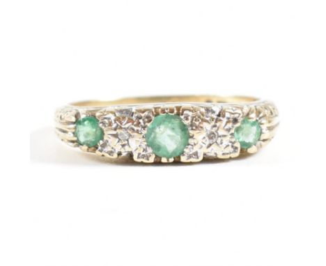 A hallmarked 9ct gold emerald and diamond gypsy ring. The ring set with three round cut emeralds with two illusion set diamon