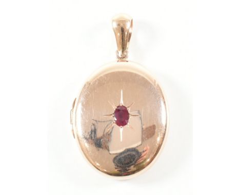 A rose gold and ruby locket pendant. The necklace locket of oval form having an oval cut star set ruby to the centre and hing