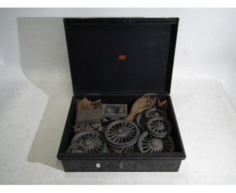 A vintage Veteran Series tin / cash box containing a quantity of cast iron wheels and other. [W]