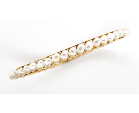 Gold and pearl bangle with approx 5.6mm x 3.7mm oval white pearl beads set in a gold frame. With an applied makers mark in Ar