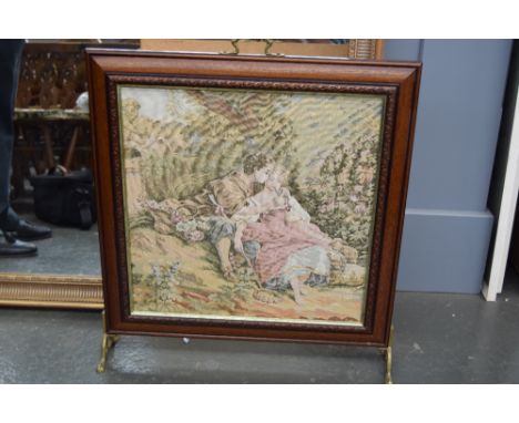 A fireguard with tapestry front depicting a courting couple with brass handle and feet 60 x 70cm