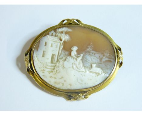 A carved shell cameo brooch, in a gold frame with ribbon crossovers at the compass points, tested as approximately 9ct gold