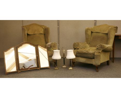 A pair of green wing armchairs, on cabriole legs, three brass Corinthian column table lamps, and a dressing table mirror