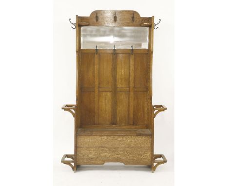 An Arts & Crafts oak settle, with a mirror back, over a winged box seat