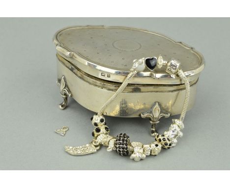 AN EARLY 20TH CENTURY SILVER TRINKET BOX, the oval outline with shaped edging and engine turned detail, vacant central circul