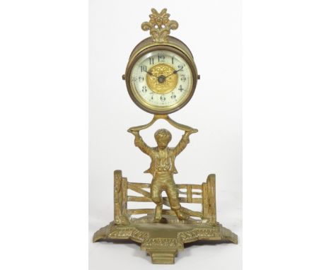 The British United Clock Co. Ltd., an early 20th century brass desk time piece, in the form of a boy seated on a gate holding