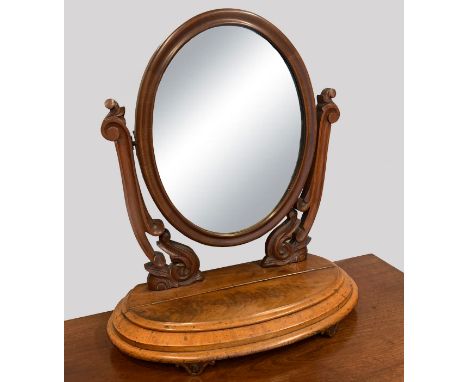 A Victorian mahogany dressing table mirror, the oval plate with foliate carved cresting, held in twin scrolling foliate carve