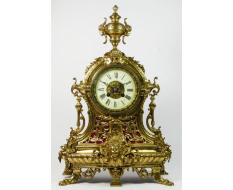 A French Gilt metal ormolu striking mantel clock with garniture, late 19th century, urn shaped finial, ringed lion central ma