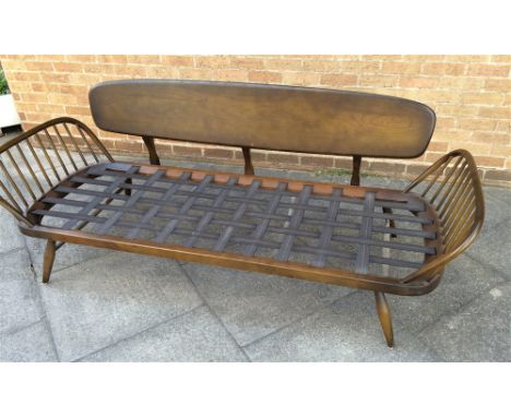 AN ERCOL MODEL 355 DAY BED,  with shaped plank back and spindle ends, lacking cushions, 208cm wide 75cm deep 77cm high
