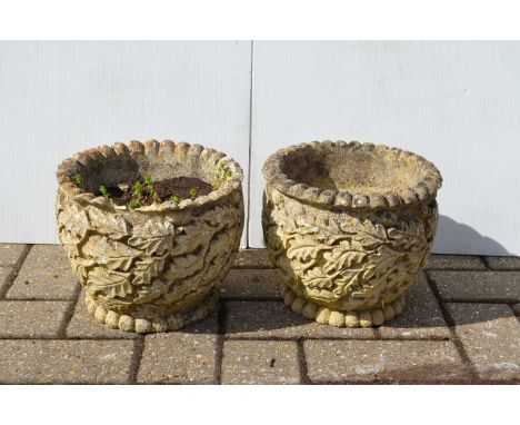 A pair of reconstituted stone planters with moulded oak-leaf decorations,  each 19cm high by 23 cm wide. (2) Damage to rim of
