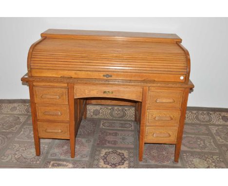 An early 20th Century light oak roll-topped or tambour partner's desk, with three drawers to either side and a central drawer