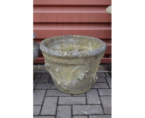 A large weathered reconstituted stone planter,  moulded with a swinging cherub pattern. 38cm high by 49 cm diameters.