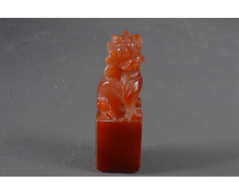A Chinese hardstone desk seal, carved from red agate in the form of a foo dog. The matrix carved with "EVA" and the equivalen