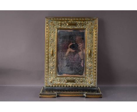 An antique pressed brass wall miror with an integral shelf, bevelled glass plate. Measures 45 cm by 32 cm wide. Attractive we