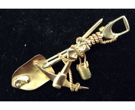 A South African Boer war period prospecting brooch; as crossed pick axe, shovel and rope, unmarked yellow metal, 57mm long, 6
